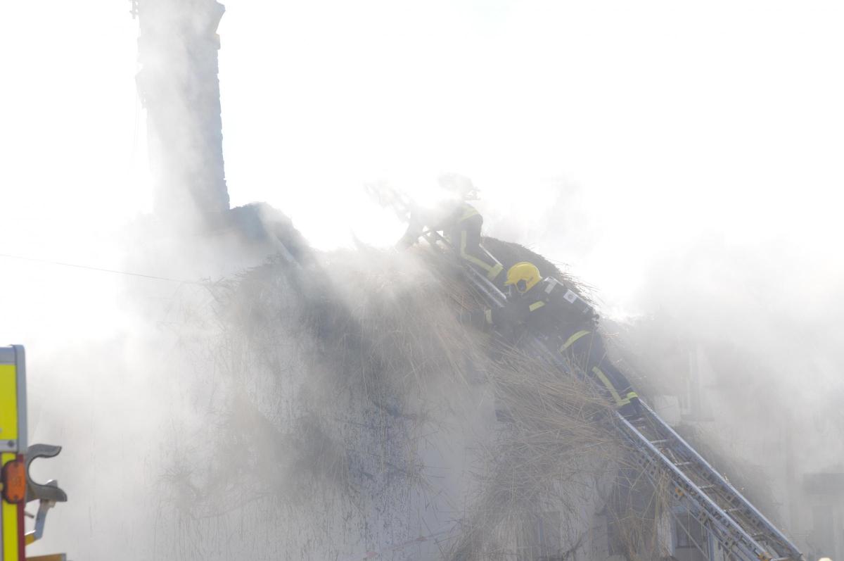Smoke billows out of the thatch