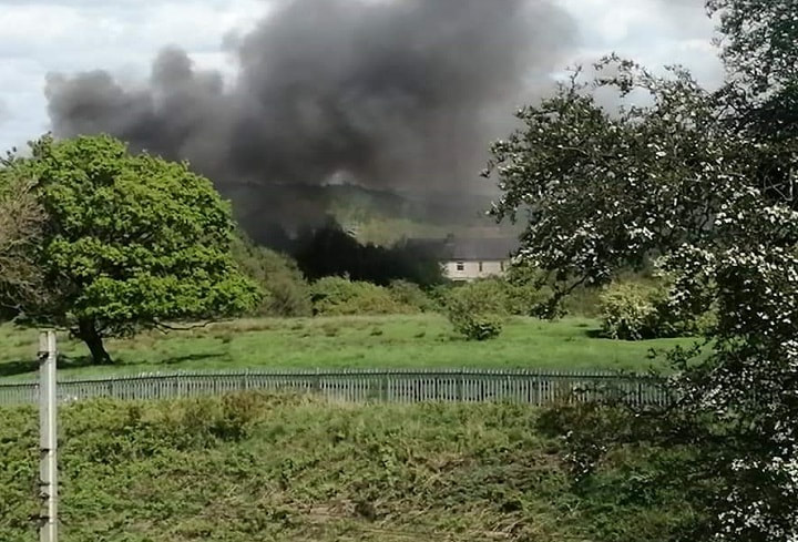 A plume of smoke rises from the old mill site