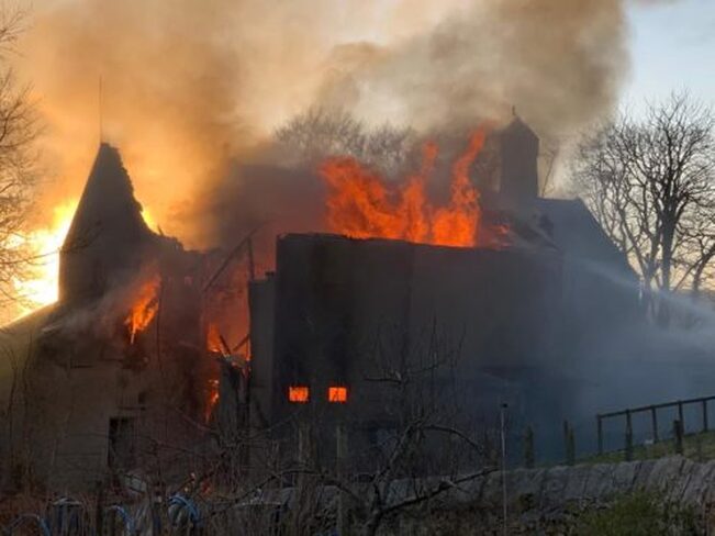  Flames can be seen on the roof of the building in Kenmure Street in Pollokshilds in Glasgow (Image: Andy Rooney) 